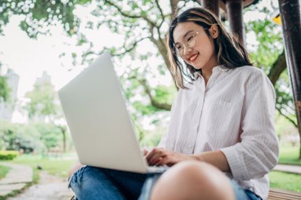 Student woman studying outdoors near tree
